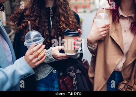 Three female friends having drinks outdoors. Happy women clinking coffee, orange juice and tea cups Stock Photo