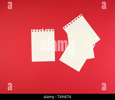 empty white sheets in a line torn out of notepad on a red background Stock Photo