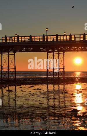 Looking under Worthing pier towards the sun setting Stock Photo