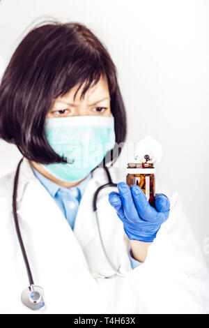 Female doctor hands  in medical gloves holding glass bottle with many different pills - Image Stock Photo