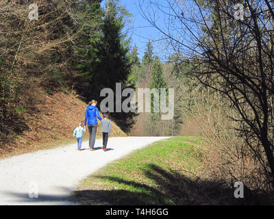 Mother with son and daughter hiking and having fun and beeing happy together and holding hands. Family trip in a forest at spring. Stock Photo