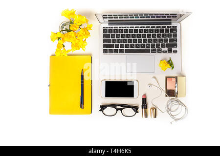 Women's workspace with laptop computer notebook, fashion glasses, makeup, mobile phone, headphones and yellow flower on white background. Stock Photo
