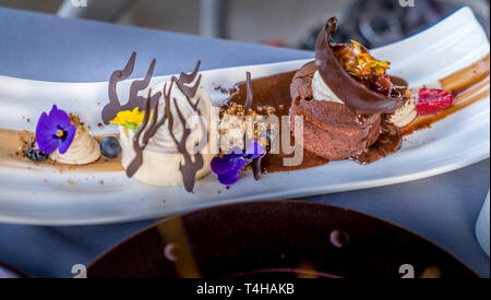 Warm Chocolate Cake with Vanilla Bean Ice Cream, Chocolate Shortbread. decorated with fresh violets and yellow pansies. Stock Photo