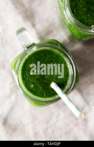 Glass jars full of green smoothie with spinach, avocado and banana, top view. Flat lay, overhead, from above. Close-up. Stock Photo