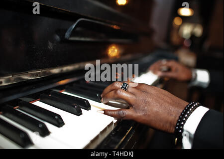 Fingers of african american man in black suit play piano. Stock Photo