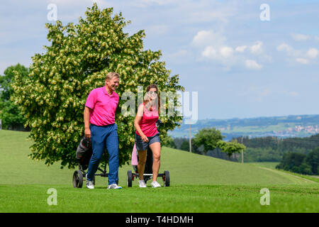 Good-humoured couple on the way on golf course Stock Photo
