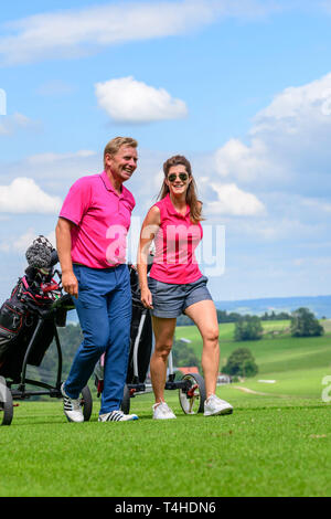 Good-humoured couple on the way on golf course Stock Photo