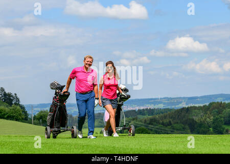 Good-humoured couple on the way on golf course Stock Photo