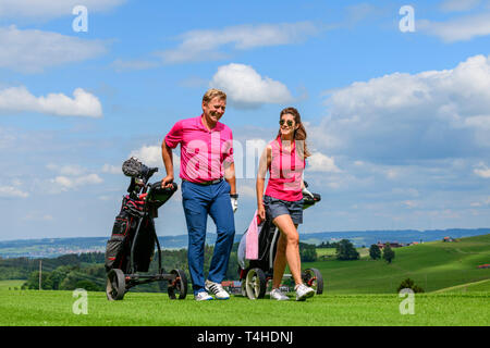 Good-humoured couple on the way on golf course Stock Photo