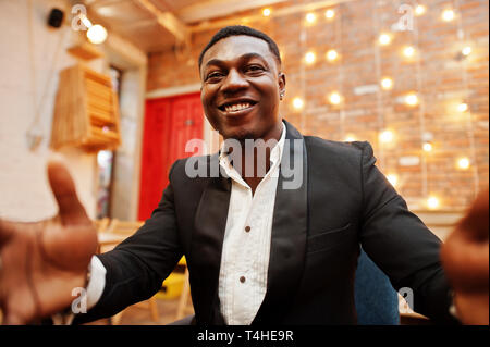 Strong powerful african american man in black suit taking selfie and holding camera with hands. Stock Photo