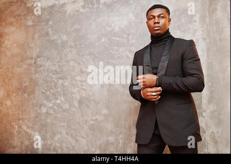 Strong powerful african american man in black suit and turtleneck posing against grey wall Stock Photo Alamy