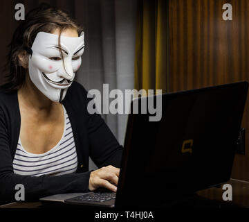 Pattaya, Thailand – November 17, 2015: A woman with Vendetta mask in front of a laptop. This mask is a well-known symbol for the online hacktivist gro Stock Photo