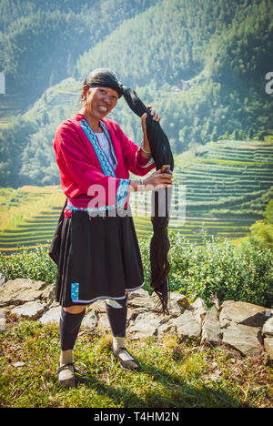 Unidentified woman brush and style hair in Longji, China. Red Yao women living in Longji Yao village, China have one of the longest hair in the world. Stock Photo