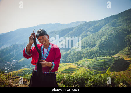 Unidentified woman brush and style hair in Longji, China. Red Yao women living in Longji Yao village, China have one of the longest hair in the world. Stock Photo