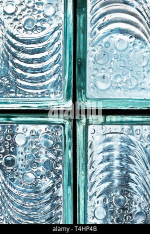 Detail of fixed blue colored glass block bricks with texture of flowing lines and bubbles, photographed against the cool bright light Stock Photo