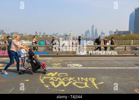 London, UK. 17th Apr, 2019. Pedestrians walk on Waterloo Bridge covered in graffiti messages on Day 3 of the  Extinction Rebellion protest  as part of an ongoing protest to force the UK Government to declare a climate crisis emergency in a 2 week campaign Credit: amer ghazzal/Alamy Live News Stock Photo