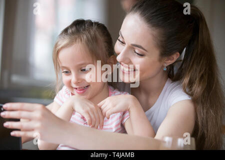 Mother and daughter having fun playing smartphone together Stock Photo