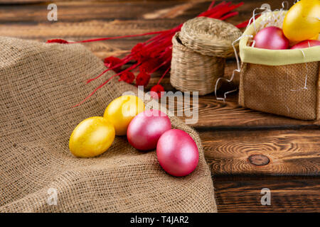 Easter eggs on a sackcloth and wooden background. Happy easter Bright multicolored shiny easter eggs. Background with easter eggs. Place for text Stock Photo