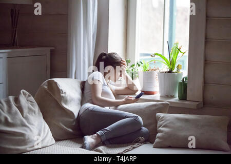 Woman upset after reading bad message on phone at home Stock Photo