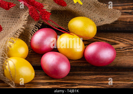 Easter eggs on a sackcloth and wooden background. Happy easter Bright multicolored shiny easter eggs. Background with easter eggs. Place for text Stock Photo