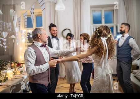 A young bride dancing with father or grandfather and other guests on a wedding reception. Stock Photo