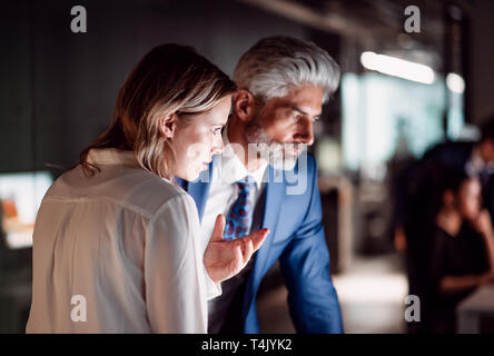 Two serious business people in an office at night., working. Stock Photo