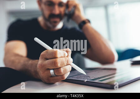 Businessman working on digital tablet and talking on cell phone. Businessman busy working in office , focus on digital tablet and stylus pen. Stock Photo