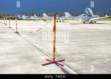 Red and yellow pole sign with a chain prohibits people of passing on an airport where small sport planes are parked and where they take off Stock Photo