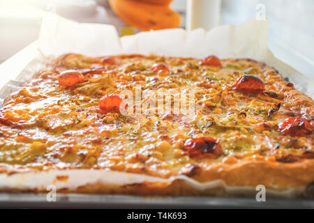 Freshly baked hot homemade pizza with red tomato vegetables and white mozzarella cheese just ready to eat Stock Photo