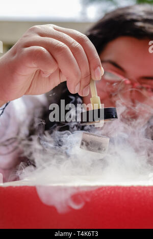 Female Student Demonstrates Quantum Magnetic Levitation and Suspension Effect. A splash of liquid nitrogen cools a ceramic superconductor forcing it t Stock Photo