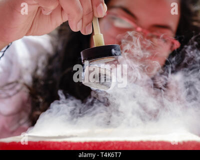 Female Student Demonstrates Quantum Magnetic Levitation and Suspension Effect. A splash of liquid nitrogen cools a ceramic superconductor forcing it t Stock Photo