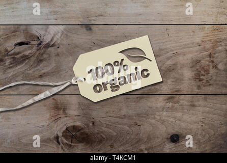 white hang tag cardboard lable with string attached an text 100 percent organic on rustic wooden table Stock Photo