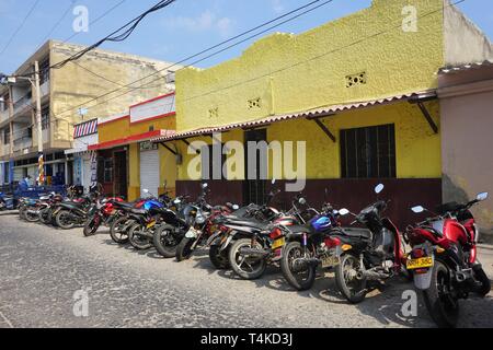 Diminishing View of a Row of Motorcycles parked in a sunlit Street Stock Photo