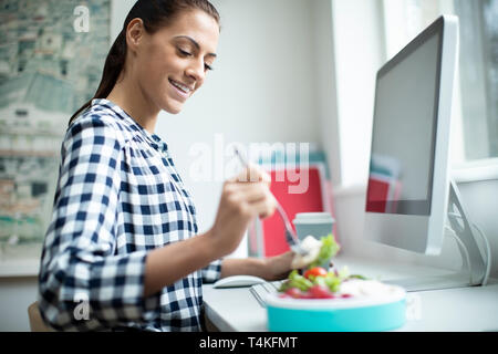 Female Worker In Office Having Healthy Chicken Salad Lunch At Desk Stock Photo