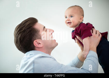 Father Lifting Smiling Baby Son Into Air At Home As They Play Gane Together Stock Photo