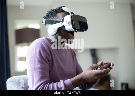 Excited Teenage Boy Playing Video Game At Home Wearing Virtual Reality Headset
