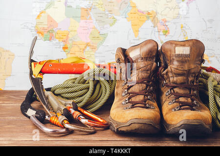 Equipment for high-altitude climbing: boots, sport ropes, carbines on the background of a geographical map. Copy space Stock Photo