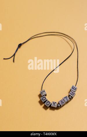 The words "look at me" spelled out by letter beads on a necklace. Stock Photo