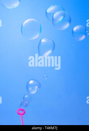 blowing soup bubbles on blue background Stock Photo