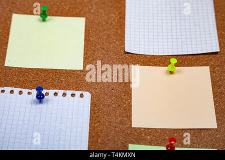 Corkboard with notes. Colored paper on corkboard. Stock Photo