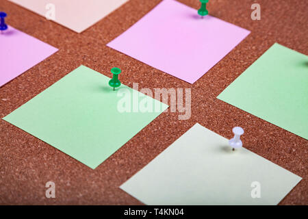 Corkboard with notes. Colored paper on corkboard. Stock Photo