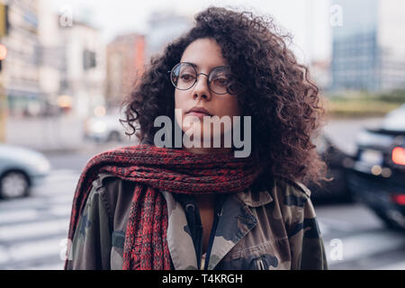 young and curly girl in the street looking ahead - cheerful, youth, awarness Stock Photo