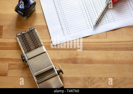 vintage adding machine on ledger purchases journal page with feather quill and ink pot Stock Photo