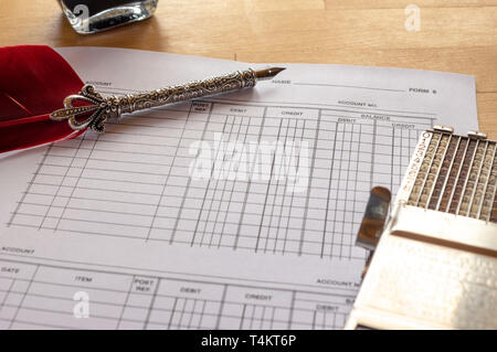 vintage adding machine on ledger accounting page with feather quill and ink pot in background Stock Photo
