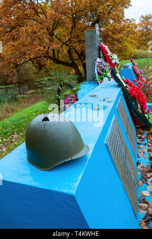 Soviet military helmets with flowers and wreath at the cemetery of fallen soldiers during World War II. Veliky Novgorod, Russia Stock Photo