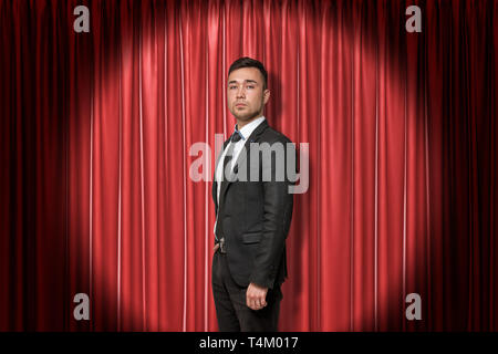 Young businessman on red stage curtains background Stock Photo