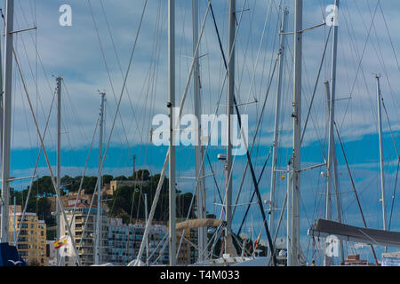 Denia, Alicante, Spain, november 21, 2018: Castle of Denia seen between the masts of sailboats moored in the harbor Stock Photo