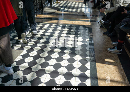 Black and white checkered floor grunge tiles marble surface at public place with interiors and people legs Stock Photo