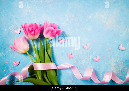 Spring holiday background. Flowers for Valentine's, Mother's or Women's Day. Pink tulips flowers on blue background. Top view, copy space Stock Photo