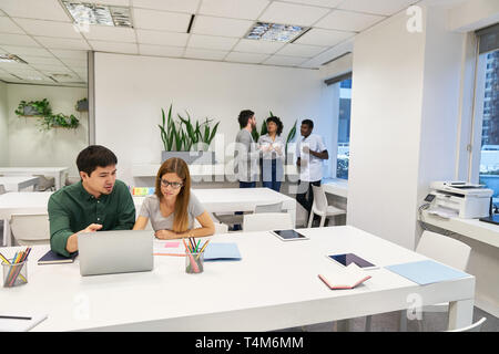Young business team in coworking office having a meeting at laptop computer Stock Photo
